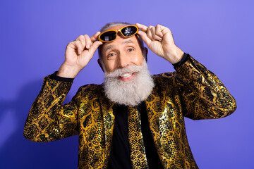 Elegant senior gentleman wearing a golden snake print jacket, adjusting sunglasses with a vibrant...