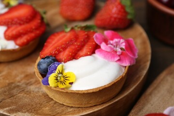 Sweet tartlets with berries and flowers on table, closeup. Delicious dessert
