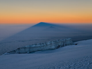 Majestic kilimanjaro casting a long shadow at sunrise over the clouds