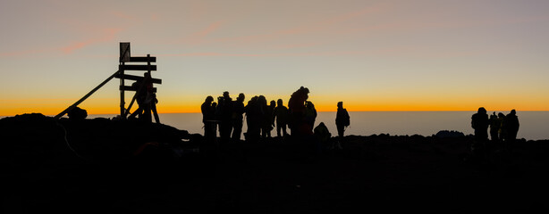 Hikers watching sunrise from uhuru peak, mount kilimanjaro.