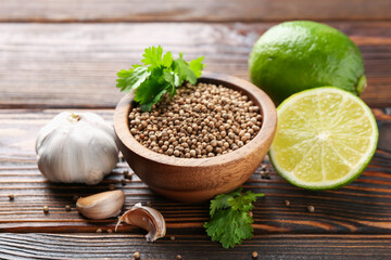 Coriander seeds, fresh cilantro, lime and garlic on wooden table, closeup