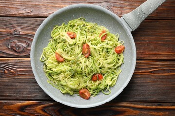 Tasty zucchini noodles with tomatoes and thyme on wooden table, top view
