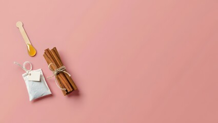Cozy Flat Lay Composition Featuring Cinnamon Sticks, Honey Dipper, and Tea Bag on a Warm Pink Background, Perfect for Wellness and Relaxation Themes