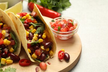 Tasty vegetarian tacos and ingredients on light grey table, closeup