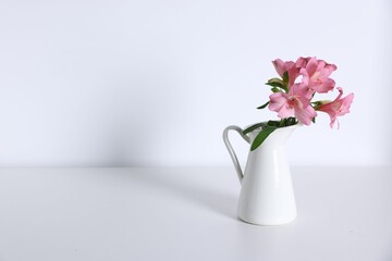 Beautiful flowers in vase on white table, space for text