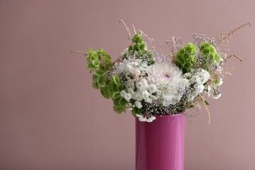 Beautiful flowers in vase on pink background, closeup. Space for text