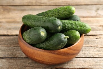 Fresh cucumbers in bowl on wooden table, closeup