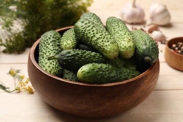 Making pickles. Fresh cucumbers in bowl on light wooden table, closeup