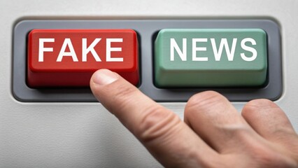 A finger is pressing a red button labeled "FAKE" next to a green button labeled "NEWS," symbolizing the concept of fake news.