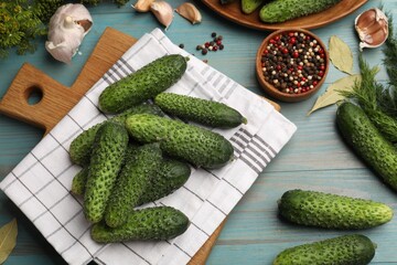Making pickles. Fresh cucumbers and other ingredients on light blue wooden table, flat lay