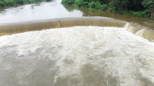 Flowing river water over small dam surrounded by greenery &ndash; natural scenic landscape footage