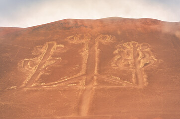 View of the ancient Candelabra geoglyph ( Candelabra of the Andes ) etched into the arid hillside of the Paracas Peninsula in Peru.