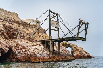 A wooden dock used for guano extraction over the rocky shore of Isla Ballesta Centro in the Ballestas Islands, Peru.