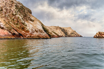 A dramatic view of the rugged coastal cliffs of the Ballestas Islands in Peru