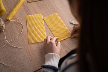 Woman rolling beeswax sheet making handmade candle