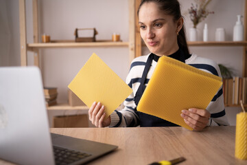 happy african american woman in eyeglasses showing handmade soap during video call on laptop in...