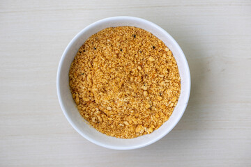 White bowl filled with delicious breadcrumbs on a wooden surface. Ideal for crunchy coatings on fried foods, binding meatballs, and as a flavorful casserole topping. High-quality food stock image.