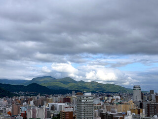 Sapporo city under a cloudy sky, with distant mountains in the background. A quiet yet dynamic view of urban and natural harmony in Hokkaido. Nature background.