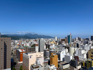 A bright, sunny day over the cityscape of Sapporo in summer. Skyscrapers and residential buildings...
