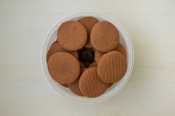 Delicious chocolate flavor biscuits in a plastic container. Tasty round cookies perfect for snacking, breakfast, or dessert. Top view.