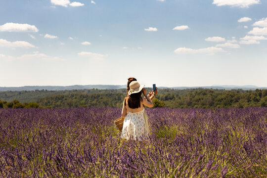 Deux femmes vue de dos portant une robe d'&eacute;t&eacute; et un chapeau se prenant en selfie dans un champ de lavande en Provence dans le Sud de la France, plateau de Valensole 
