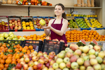 Female salesman in an apron carefully places ripe apples on a supermarket counter