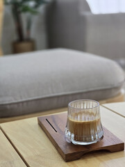 glass of beverage rests on wooden coaster, showcasing cozy interior setting with soft furnishings...