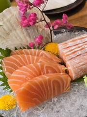 Fresh salmon sashimi served on ice with decorative flowers and greens, showcasing vibrant colors and textures. delightful presentation for seafood lovers