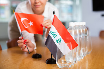 Female employee of the delegation sets flags of countries of Turkey and Iraq on the table before...