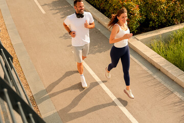 Running together along a peaceful path surrounded by greenery in the bright morning sun