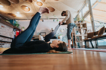 A yoga practice session with partners assisting each other in a welcoming and tranquil indoor studio.