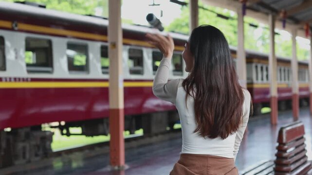 Woman waving goodbye at train station