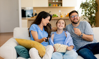 Family enjoying a cozy movie night at home while sharing laughter and popcorn