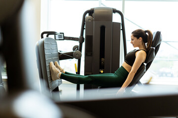 Fitness enthusiast working hard on leg press machine in modern gym setting during afternoon workout session