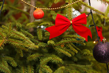 A close-up of a decorated Christmas tree with red bows, colorful ornaments, and golden beads.