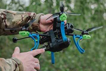 Person military in camouflage adjusting a custom FPV drone with an attached training munition