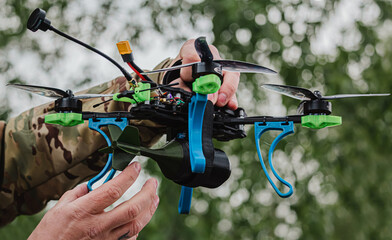 Person military in camouflage adjusting a custom FPV drone with an attached training munition