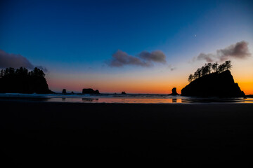 Obraz premium Sunset at Second Beach, Olympic National Park, Washington. Silhouettes of sea stacks and gentle ocean waves under a glowing sky.