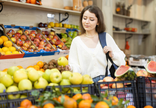 Happy girl choosing ripe apples in grocery supermarket - Powered by Adobe