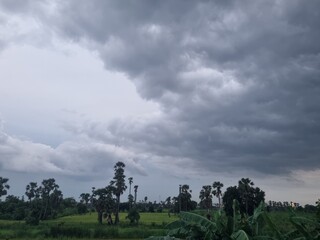Cloudy Sky over Countryside: A vast, dramatic skyscape is dominated by ominous, textured clouds,...