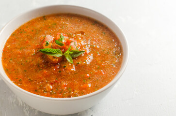 Cold summer soup Gazpacho in a gray bowl on a gray background. Traditional Spanish cuisine concept. Vegan or vegetarian. Selective focus. Horizontal orientation. Copy space.