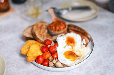 English breakfast menu fried eggs baked beans in grilled tomato and bacon sausage in plate on table traditional tasty meal