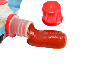 A puddle on a white background formed from ketchup squeezed out of a soft container.