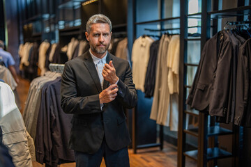 Retail assistant help stylish man to find suit. Stylish man in suit. Businessman choose elegant...