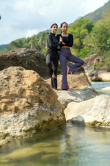 Asian Indonesian Women Doing Yoga Exercise in Nature on Rocky Riverside