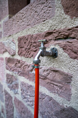 Outdoor water tap faucet, with garden hose attached, for watering of grass lawn and flowers. Concept water rationing, gardening.