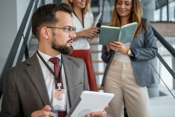 Businessman holding tablet talking to colleagues on stairs in office building