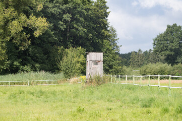 Wooden hunting blind overlooking lush green field and forest