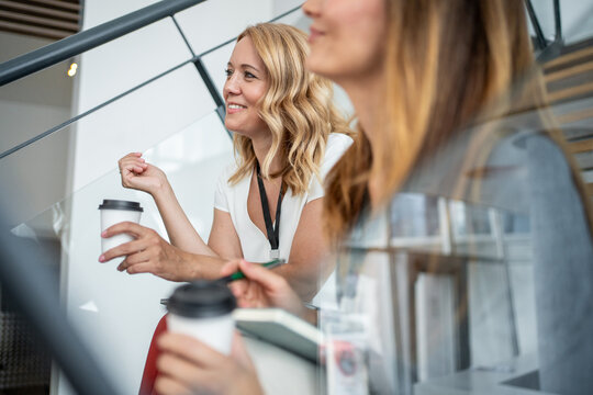 Businesswomen sitting on stairs during coffee break at conference