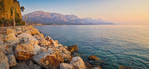 Panoramic view of Kemer coastline with majestic Taurus mountains towering over the calm sea in the morning at sunrise. Turkey mediterranean sea coast panorama